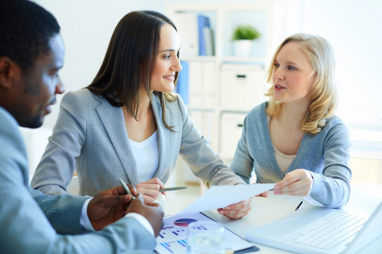 Two women in business suits are sitting at a table.